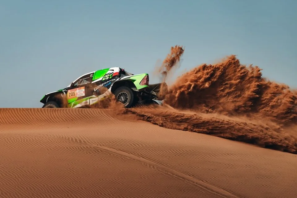 Auto des Energylandia Rally Team wirbelt auf einer Düne eine Sandfahne auf