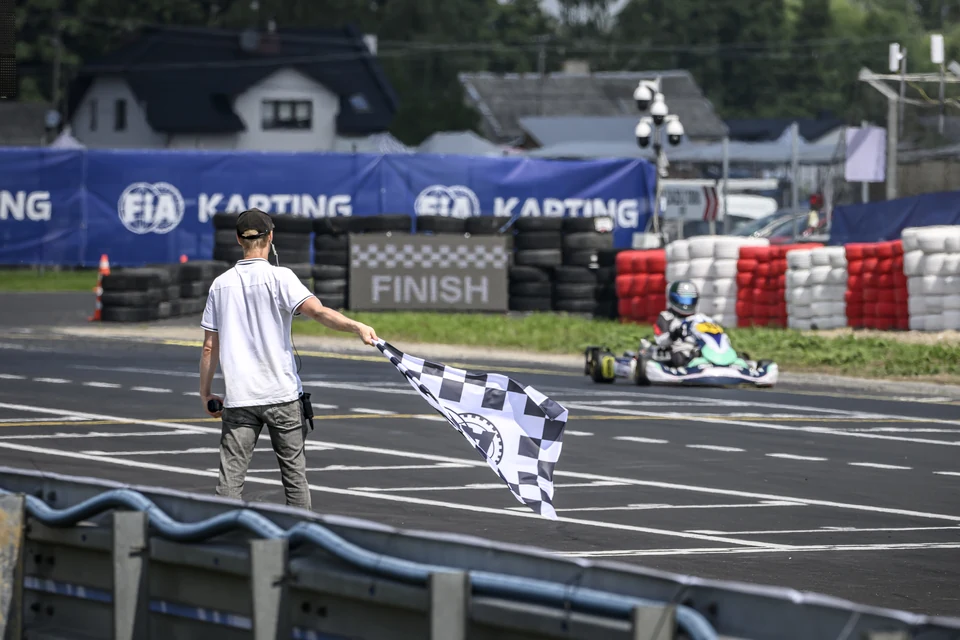 Flaga w szachownicę na linii mety: gokart przejeżdża pod flagą w Słomczynie