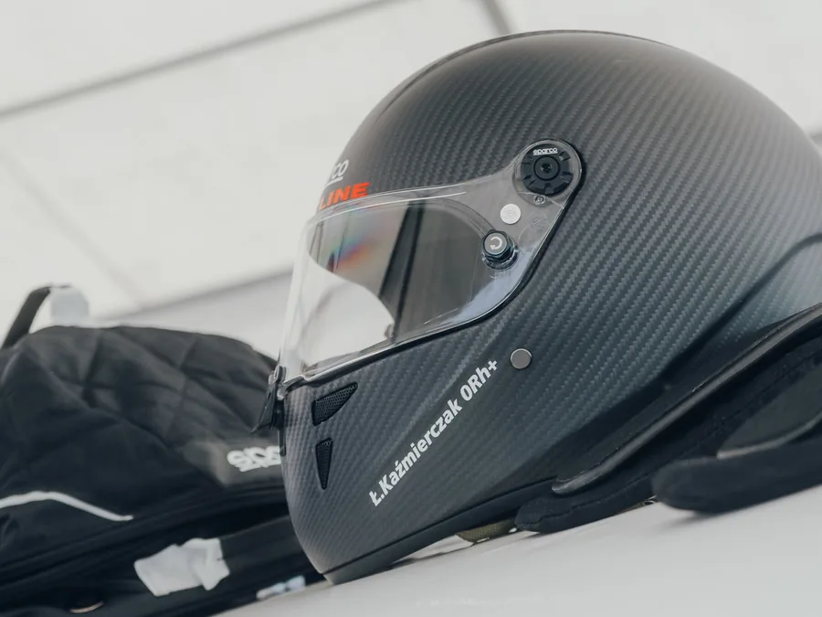 Karbonowy kask Łukasza Kaźmierczaka na dachu auta wyścigowego