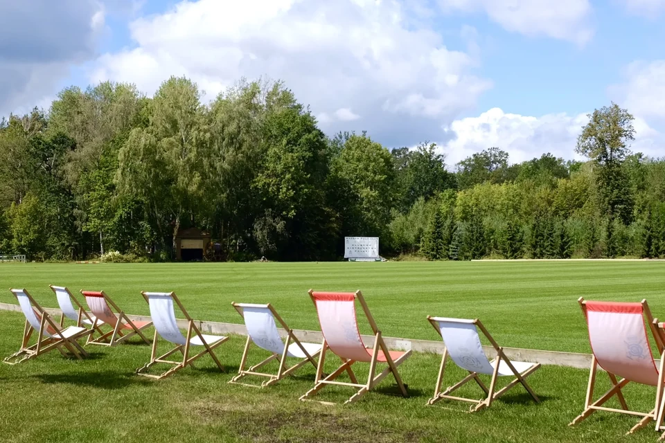Banen på Warsaw Polo Club i sol, en række liggestole langs sidelinjen og skov i baggrunden